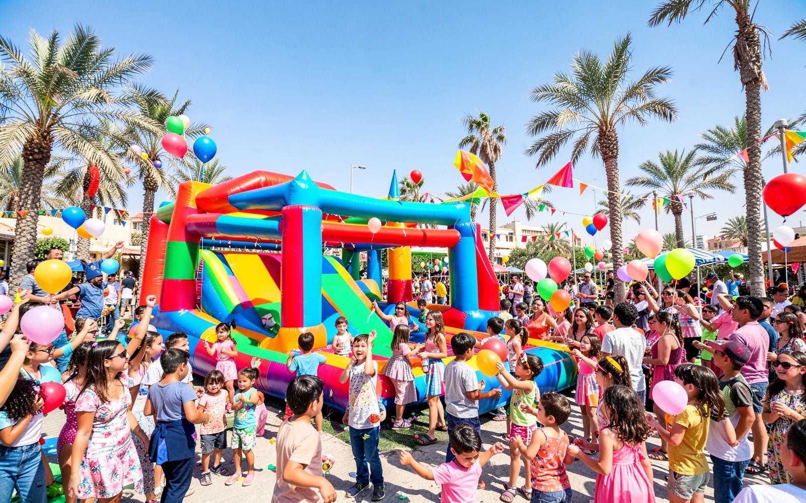 Families celebrating at a PLAYDROP party in Muscat with inflatables and balloons